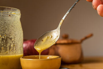 Drips of Oil and Dressing into a glass container in preparation for a salad dressing.
