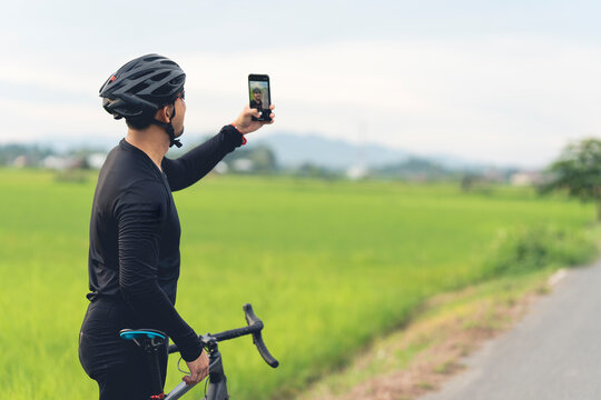 A cyclist using a smartphone to take a selfie after finishing his bike, looks fun.