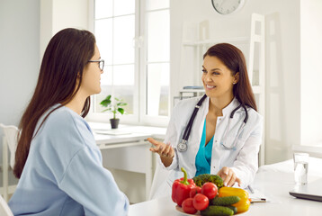 Friendly female nutritionist advises woman on diet plan and talk about benefits of raw vegetables....