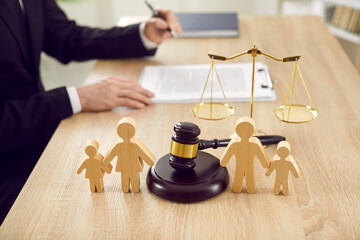 Figures of family are separated by judge's gavel, which symbolizes divorce case and custody of...