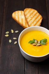 Pumpkin soup with toasts on wooden table.