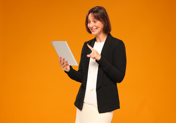 businesswoman uses tablet isolated on yellow background with joyful surprised emotion. business online banking technology concept