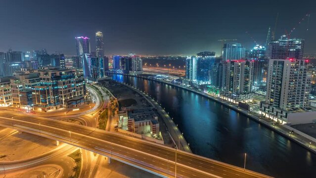 Skyscrapers and towers at the Business Bay aerial day to night transition timelapse in Dubai, United Arab Emirates. Panoramic view from above with canal after sunset