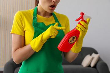 Woman pointing at bottle of toxic household chemical with warning sign, closeup