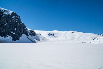 Landscape of a frozen lake with mountains in the background and lots of snow in Norway.