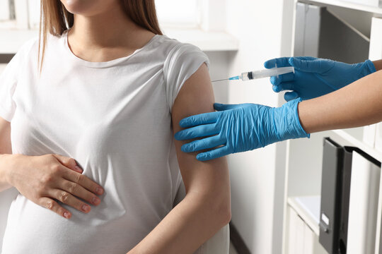 Doctor giving injection to pregnant woman in hospital, closeup