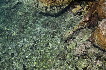Fototapeta na wymiar Shallow water with rocky sea bottom as background, top view