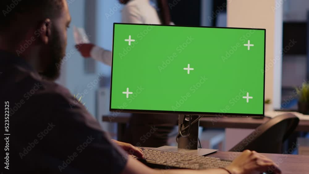 Poster african american man looking at computer with greenscreen, analyzing isolated display on desktop mon