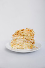 Piece of Napoleon cake on a white saucer isolated on a white background. Cake of puff pastry with sour cream. Copy space.