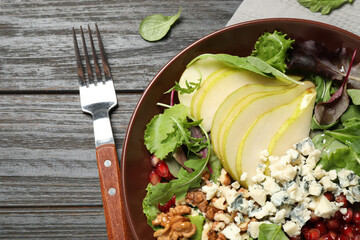 Tasty salad with pear slices served on black wooden table, flat lay