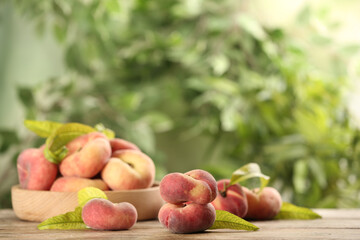 Fresh ripe donut peaches on wooden table against blurred green background. Space for text
