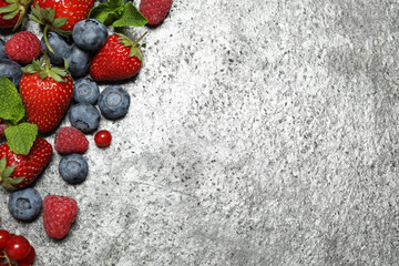 Different fresh berries on grey background, flat lay. Space for text