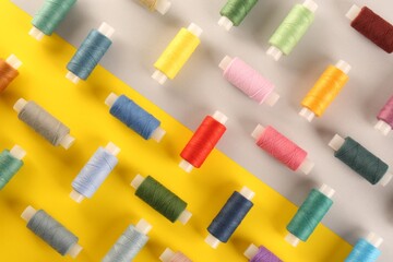 Different sewing threads on color background, flat lay