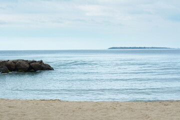 Beautiful view on sea with rock breakwater near sandy beach