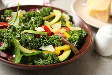 Tasty fresh kale salad on light grey table, closeup