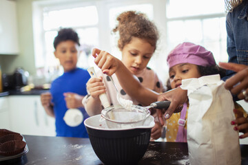 Family baking sifting flour in kitchen