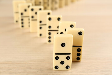 White domino tiles with black pips on wooden table, closeup