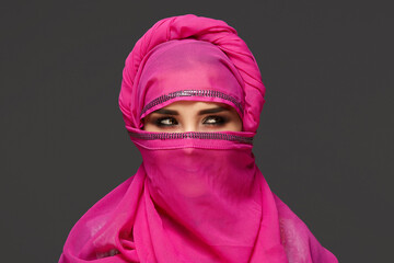 Naklejka premium Close-up shot of a young charming woman wearing the pink hijab decorated with sequins. Arabic style.