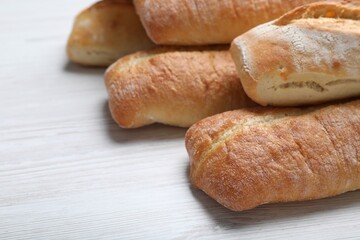 Tasty baguettes on white wooden table, closeup. Space for text