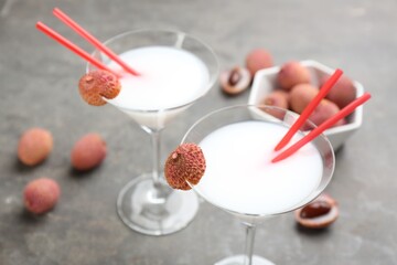 Lychee cocktail with fresh fruits on grey table, closeup