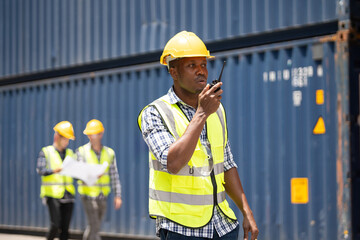 Black African engineer man worker working in container port terminal. Attractive foreman worker processes orders and product at warehouse logistic in cargo freight ship for import and export in harbor