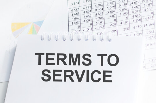 TERMS OF SERVICE text on notepad on the background of reports and charts on the table