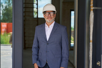 Portrait of man in suit, glasses and protective helmet