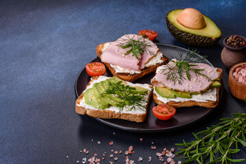 Fresh, delicious ham, butter, avocado and sesame seeds sandwiches on a wooden cutting board