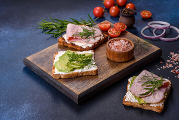 Fototapeta na wymiar Fresh, delicious ham, butter, avocado and sesame seeds sandwiches on a wooden cutting board