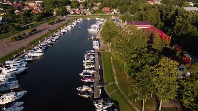 Arial right to left pan and motion shot of a small Marina with private ships and boats docked. Europe.