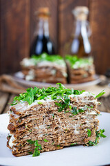 Liver cake on wooden background. Sliced layered liver cake with mayonnaise