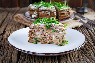 Liver cake on wooden background. Sliced layered liver cake with mayonnaise