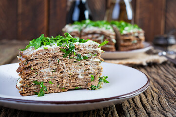 Liver cake on wooden background. Sliced layered liver cake with mayonnaise