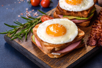 Fresh, delicious sandwiches with fried egg, ham, butter, avocado and sesame seeds