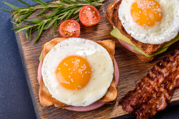 Fresh, delicious sandwiches with fried egg, ham, butter, avocado and sesame seeds