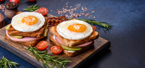 Fresh, delicious sandwiches with fried egg, ham, butter, avocado and sesame seeds