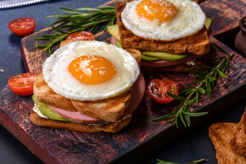 Fresh, delicious sandwiches with fried egg, ham, butter, avocado and sesame seeds