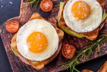 Fresh, delicious sandwiches with fried egg, ham, butter, avocado and sesame seeds