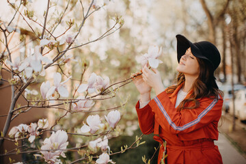 Portrait of beautiful young woman with blooming tree in spring in park.