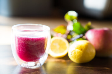 A glass of organic beetroot smoothie with fruits background on wooden table.