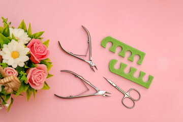 Set of tools for simple manicure and pedicure - scissors, tweezers and pedicure tools on pink background with flowers