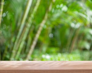 Empty board or table top and blurred green bamboo culms. Place for your product display.