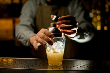close-up of transparent shaker with liquid a which the hand of bartender carefully closes with a lid