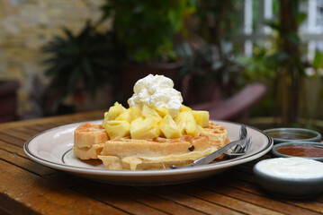 Belgium waffles with pineapple fruit and ice cream on a plate