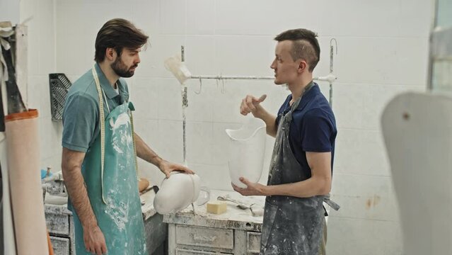 Young Caucasian craftsman standing in front of new employee explaining how to craft comfortable socket for prosthesis
