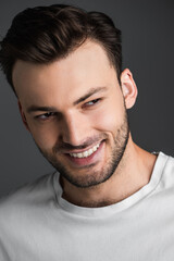 Portrait of cheerful young man looking away isolated on grey.