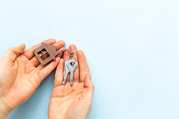 Hands holding house shaped keychain and keys. Real estate concept