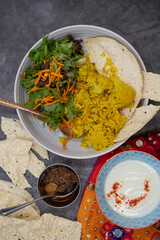 Vegetarian indian rice and cauliflower pilaf, papad and salad along with pickles and yougurt