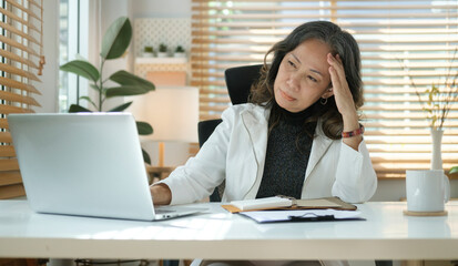 Stressed mature senior business woman suffering from headache or migraine.