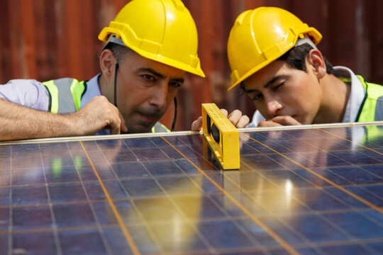 asian university student learning alternative sustainable energy and set up solar panel with professor. engineering team working on checking and maintenance solar cell on rooftop of factory building.
